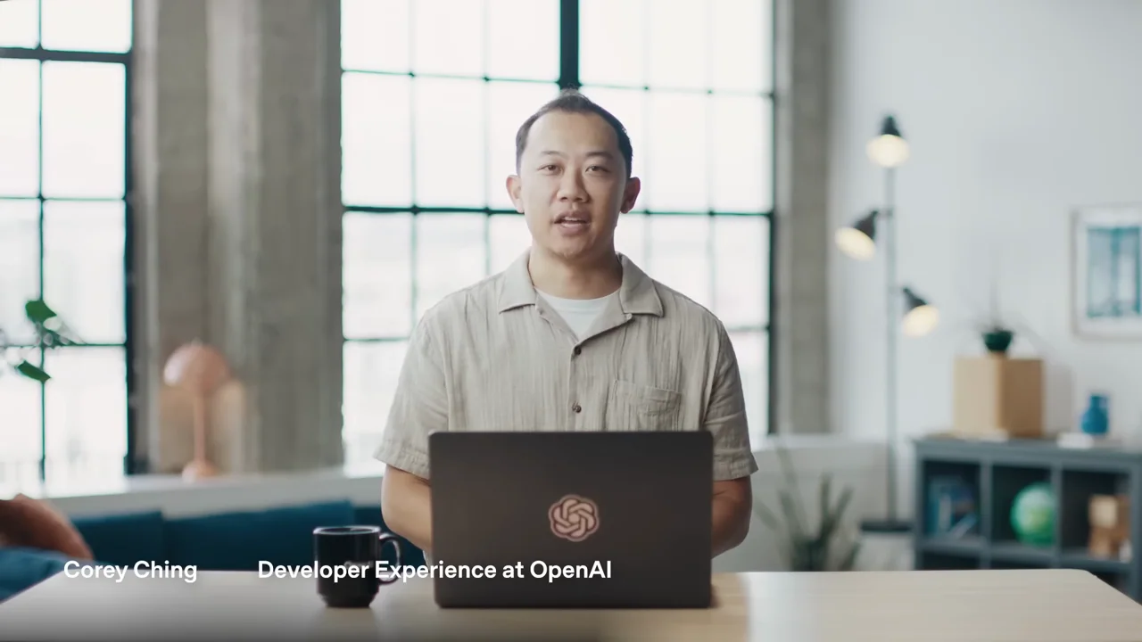 The speaker appears behind a laptop with a lower-third label.
