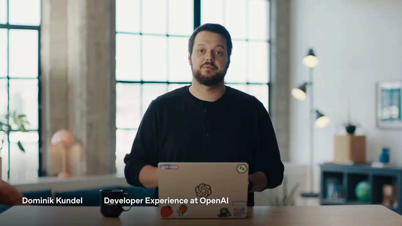 A standing presenter introduces the topic behind a laptop.