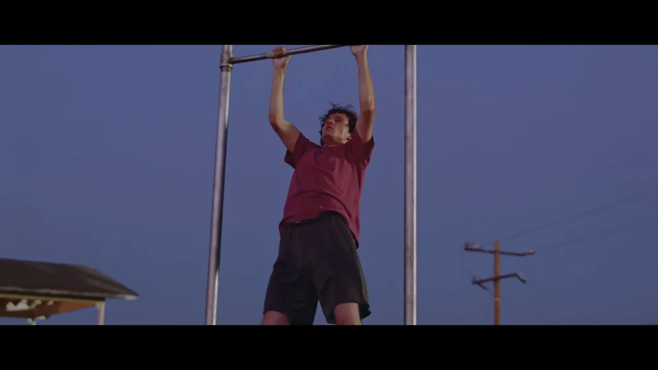 The person and exercise bar become visible against the evening sky.