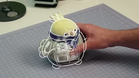 Source frame at 25.500s. Parts layout, coding laptop, toy with circuitry overlay.